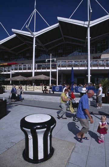 ENGLAND, Hampshire, Portsmouth, Gunwharf Keys. Waterfront restaurants and bars overlooking the marina with people walking past on the pedestrian walkway