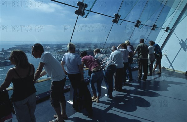 ENGLAND, Hampshire, Portsmouth, "Gunwharf Quays. The Spinnaker Tower. Interior with visitors looking out of glass windows on the top observation deck, providing a 320° view of the city of Portsmouth, the Langstone and Portsmouth harbours, and a viewing distance of 37 kilometres (23 miles)"