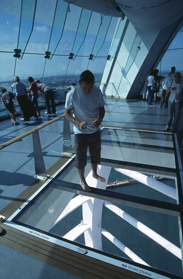 ENGLAND, Hampshire, Portsmouth, Gunwharf Quays. The Spinnaker Tower. Interior on the observation deck with a man standing on a glass floor viewing the harbour below.