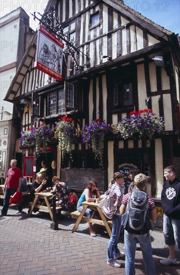 ENGLAND, East Sussex, Hastings, Old Town. George Street . Tmbered frontage of Ye Olde Pump House pub with people sitting outside at tables under hanging baskets
