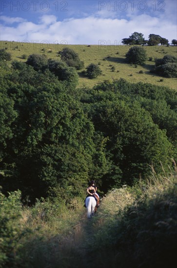 ENGLAND, East Sussex, Plumpton, Horse riders on a bridlepath at the foot of the South Downs.