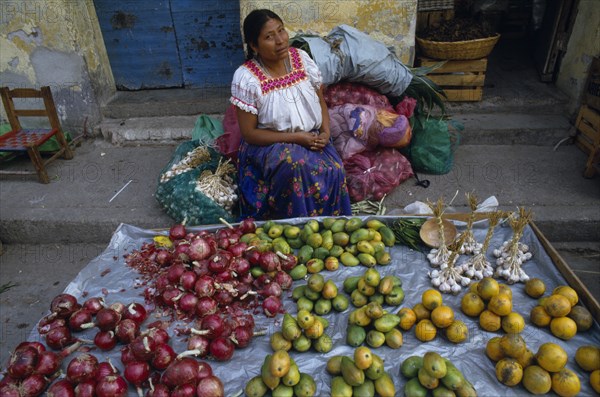 MEXICO, Guerrero, Markets, "Woman sitting behind street stall display selling onions, garlic and fruit."