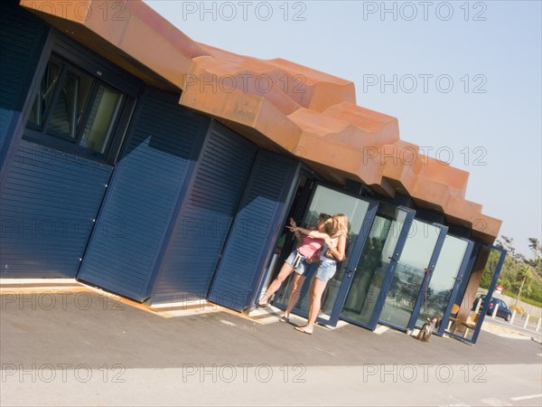 ENGLAND, West Sussex, Littlehampton, Two women standing by glass door at the East Beach Cafe designed by Thomas Heatherwick