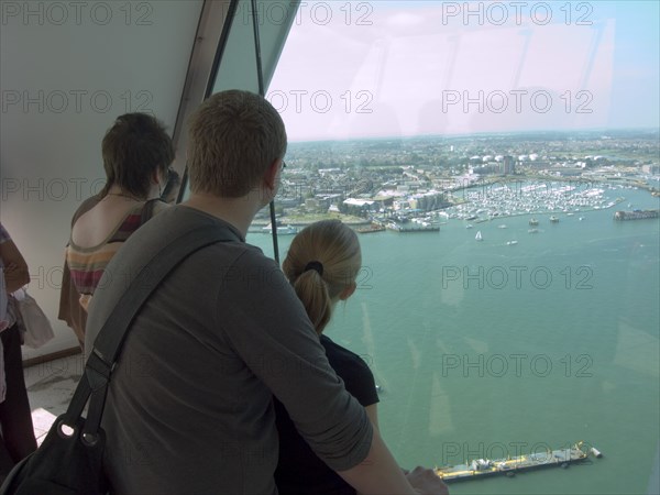 ENGLAND, Hampshire, Portsmouth, "Gunwharf Quays. The Spinnaker Tower. Interior view with visitors looking out of glass windows on the top observation deck, providing a 320° view of the city of Portsmouth, the Langstone and Portsmouth harbours, and a viewing distance of 37 kilometres (23 miles)"