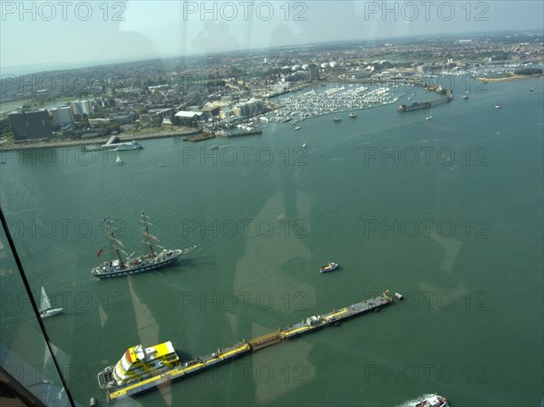 ENGLAND, Hampshire, Portsmouth, Gunwharf Quays. The Spinnaker Tower. View looking out of a glass window on the observation deck across the harbour towards Gosport with Ferries and a tall ship seen on water