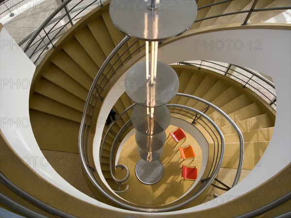 ENGLAND, East Sussex, Bexhill-on-Sea, The De La Warr Pavilion. Interior view down the helix staircase with chrome Bauhaus globe lamps. Three colourful chairs seen at the bottom