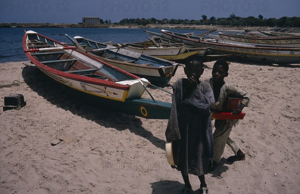 SENEGAL, Fishing, Two children on beach beside line of painted fishing boats pulled up onto the sand.
