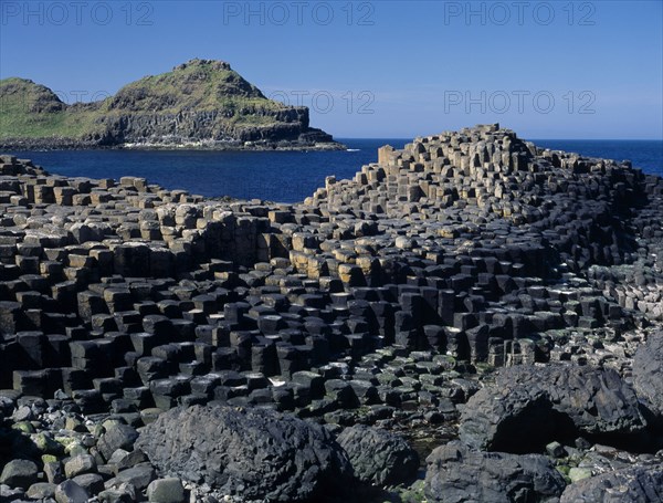 NORTHERN IRELAND, County Antrim, Giants Causeway, Interlocking basalt stone columns left by volcanic eruptions. View across the main and most visited section of the causeway with the coastline seen behind.