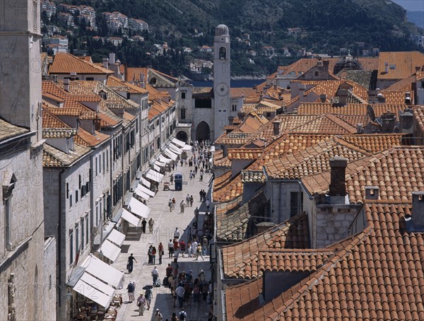 CROATIA, Dalmatia, Split, "Elevated view over terracotta tiled rooftops and Stradun, the main street in the Old City which is lined with cafes and bars leading towards The Franciscan Monastery Church."