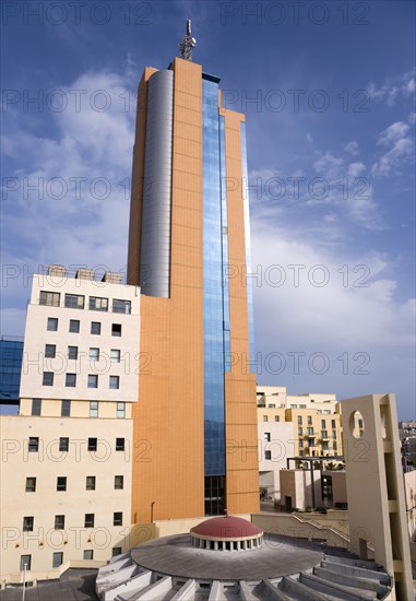 MALTA, Saint Julians, Portomaso Hilton Tower office complex towering above a small church with dome and bell tower