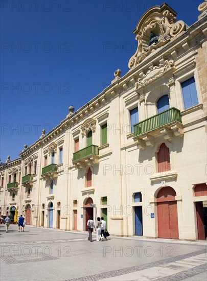 MALTA, Valletta, People walking by the waterfront redevelopment of old Baroque Pinto wharehouses below the bastion walls of Floriana beside the cruise ship terminal