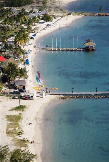 WEST INDIES, St Lucia, Gros Islet , "The coconut palm tree lined beach at Sandals Grande St Lucian Spa and Beach Resort hotel with tourists walking, swimming or sunbathing"