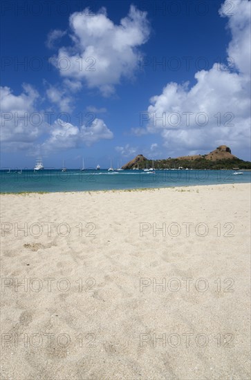 WEST INDIES, St Lucia, Gros Islet , Pigeon Island National Historic Park seen from a nearby beach on a causeway to the island with yachts at anchor in Rodney Bay