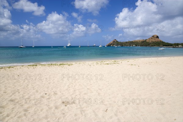 WEST INDIES, St Lucia, Gros Islet , Pigeon Island National Historic Park seen from a nearby beach on a causeway to the island with yachts at anchor in Rodney Bay