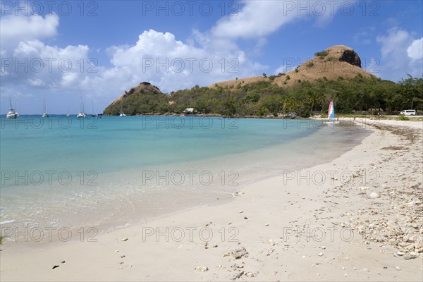 WEST INDIES, St Lucia, Gros Islet , Pigeon Island National Historic Park seen from a nearby beach on a causeway to the island with yachts at anchor in Rodney Bay