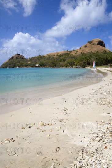 WEST INDIES, St Lucia, Gros Islet , Pigeon Island National Historic Park seen from a nearby beach on a causeway to the island with yachts at anchor in Rodney Bay