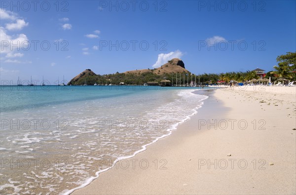 WEST INDIES, St Lucia, Gros Islet , The beach at Sandals Grande St Lucian Spa and Beach Resort hotel with Pigeon Island National Historic Park beyond