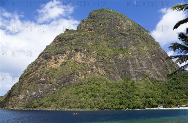 WEST INDIES, St Lucia, Soufriere , Val des Pitons The white sand beach at the Jalousie Plantation Resort Hotel with the volcanic plug of Petit Piton beyond and tourists on sunbeds beneath palapa sun shades