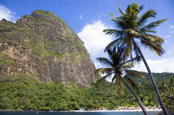 WEST INDIES, St Lucia, Soufriere , Val des Pitons The white sand beach at the Jalousie Plantation Resort Hotel with the volcanic plug of Petit Piton beyond and tourists on sunbeds beneath palapa sun shades