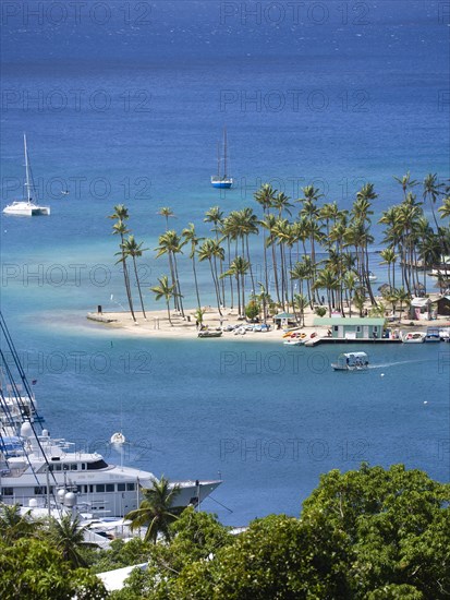 WEST INDIES, St Lucia, Castries , Marigot Bay Yachts at anchor beyond the small coconut palm tree lined beach of the Marigot Beach Club sitting at the entrance