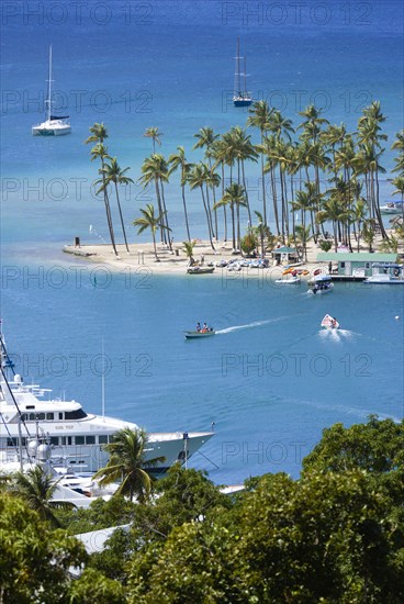 WEST INDIES, St Lucia, Castries , Marigot Bay Yachts at anchor beyond the small coconut palm tree lined beach of the Marigot Beach Club sitting at the entrance