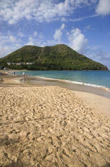 WEST INDIES, St Lucia, Gros Islet, Reduit Beach in Rodney Bay during the early morning with tourists walking by the waterline