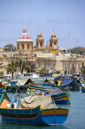 MALTA, Marsaxlokk , Fishing village harbour on the south coast with colourful Kajjiki fishing boats and the Church dedicated to Our Lady of the Rosary The Madonna of Pompeii