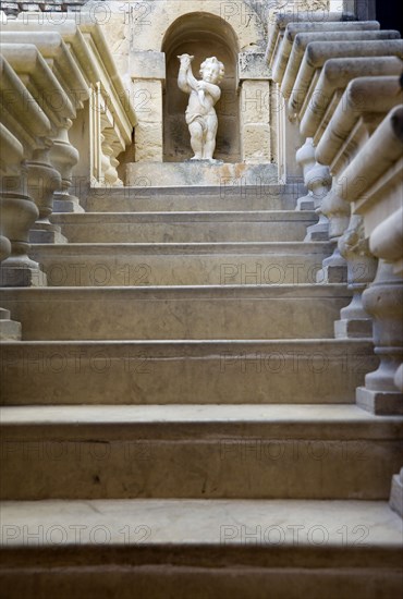 MALTA, Mdina, The Silent City. Statue of a cherub at the top of stone steps in the Fontanella Tearooms garden