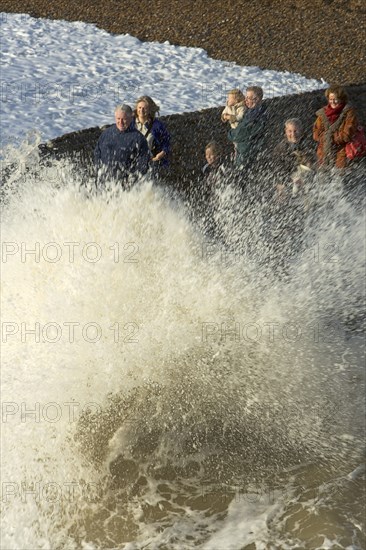 ENGLAND, East Sussex, Brighton, Waves crashing onto beach and groyne with people getting wet.