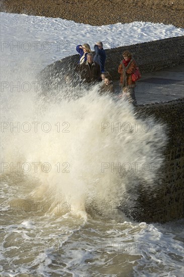 ENGLAND, East Sussex, Brighton, Waves crashing onto beach and groyne with people getting wet.