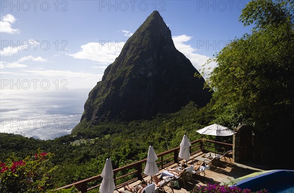 WEST INDIES, St Lucia, Soufriere , Val des Pitons Tourists sunbathing on the sun deck beside the pool at Ladera Spa Resort Hotel overlooking Petit Piton volcanic plug and Jalousie beach