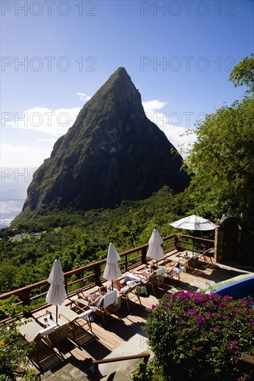WEST INDIES, St Lucia, Soufriere , Val des Pitons Tourists sunbathing on the sun deck beside the pool at Ladera Spa Resort Hotel overlooking Petit Piton volcanic plug and Jalousie beach