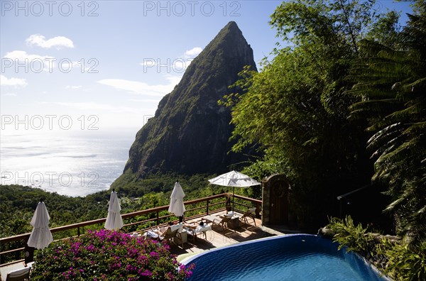 WEST INDIES, St Lucia, Soufriere , Val des Pitons Tourists sunbathing on the sun deck beside the pool at Ladera Spa Resort Hotel overlooking Petit Piton volcanic plug and Jalousie beach