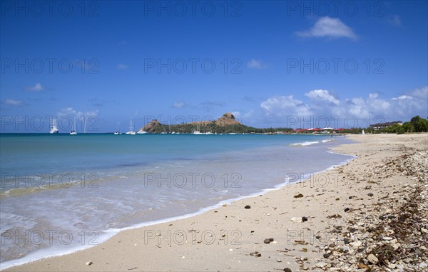 WEST INDIES, St Lucia, Gros Islet , Pigeon Island National Historic Park seen from a nearby beach on a causeway to the island with yachts at anchor in Rodney Bay