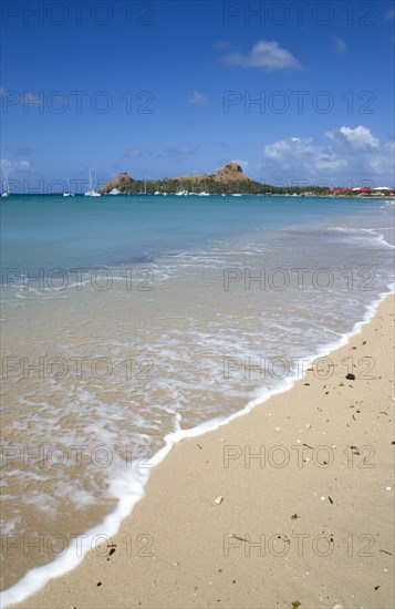 WEST INDIES, St Lucia, Gros Islet , Pigeon Island National Historic Park seen from a nearby beach on a causeway to the island with yachts at anchor in Rodney Bay