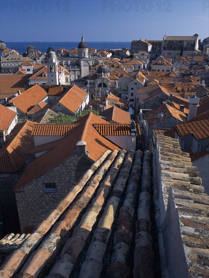 CROATIA, Dalmatia, Dubrovnik, "Elevated view over terracotta roof tops towards the Cathedral, St Blaise’s Church and clock tower in morning light."