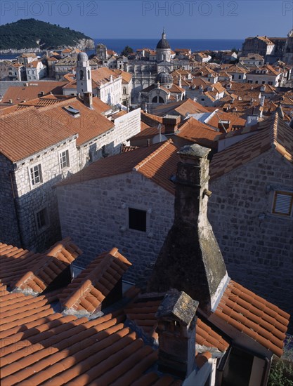 CROATIA, Dalmatia, Dubrovnik, "Elevated view over terracotta roof tops towards the Cathedral, St Blaise’s Church and clock tower in morning light."