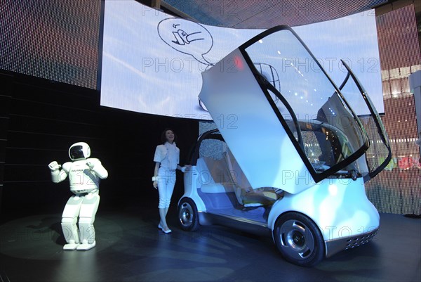 JAPAN, Honshu, Chiba, "2007 Tokyo Car Show, Honda exhibit, Asimo Robot presents Honda concept car Puyo, young woman opens car's gull-wing doors"