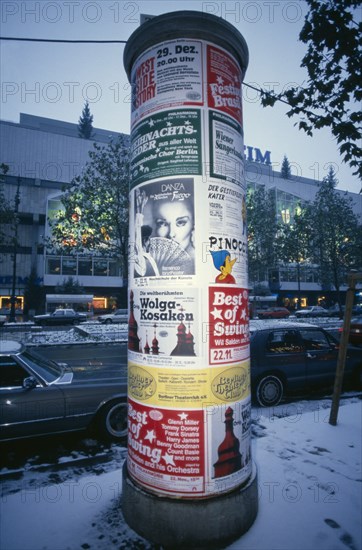 GERMANY, Berlin, Poster pillar along Kurfurstendamm commercial street in West Berlin at winter time
