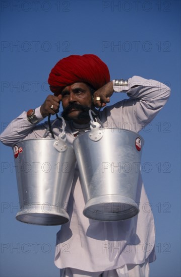 INDIA, Rajasthan, Bikaner, Rajput man lifting buckets of water with his moustache during the Camel Festival.