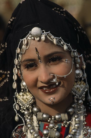 INDIA, Rajasthan, Jaisalmer, Head and shoulders portrait of a Miss Desert contestant  wearing traditional jewellery at the Desert Festival