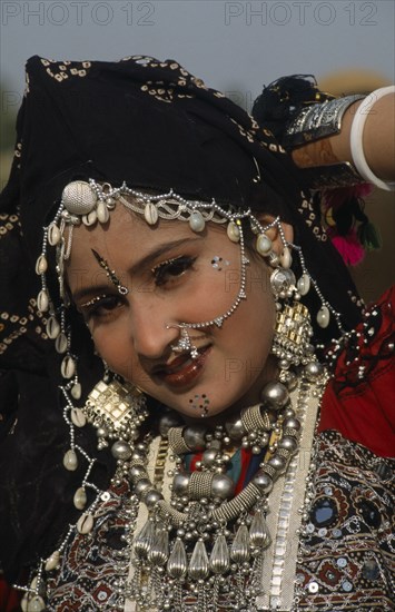 INDIA, Rajasthan, Jaisalmer, Head and shoulders portrait of a Miss Desert contestant  wearing traditional jewellery at the Desert Festival