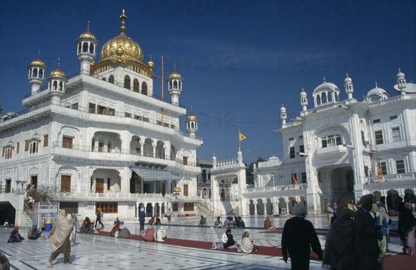 INDIA, Punjab, Amritsar, "The Sri Takhat Sahib, Sikh Parliment building in the Golden Temple complex with groups of people gathered on marble floor"