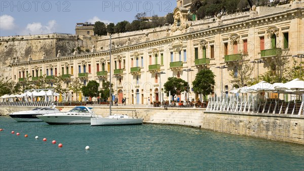 MALTA, Valletta, The waterfront redevelopment of old Baroque Pinto wharehouses below the bastion walls of Floriana beside the cruise ship terminal with boats moored alongside
