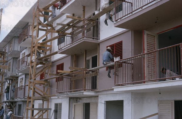 CUBA, Industry, Construction workers and painters on wooden scaffolding working on muli-storey building exterior.