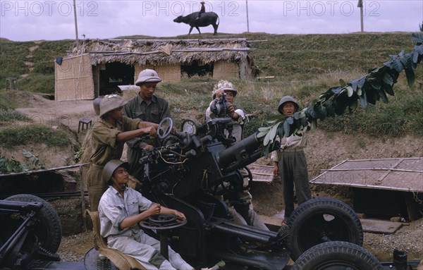 VIETNAM, North Central, Thanh Hoa, "Members of Militia unit, not regular army with anti-aircraft missile launcher.  Child riding water buffalo on crest of hill behind."