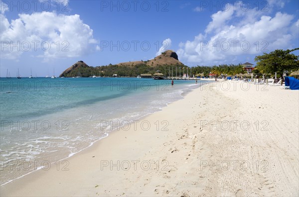 WEST INDIES, St Lucia, Gros Islet , The beach at Sandals Grande St Lucian Spa and Beach Resort hotel with Pigeon Island National Historic Park beyond