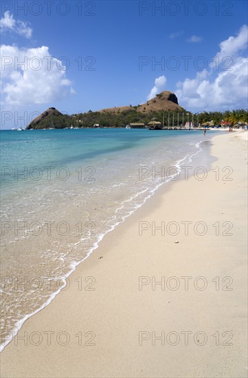 WEST INDIES, St Lucia, Gros Islet , The beach at Sandals Grande St Lucian Spa and Beach Resort hotel with Pigeon Island National Historic Park beyond