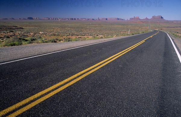 USA, Arizona , Monument Valley, "View from US Highway 163 across empty stretch of road leading to the valley with red mesas, buttes and pinnacles of rock seen in the distance"