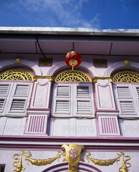 MALAYSIA, Penang, Georgetown, Pink and gold painted shopfront with wooden window shutters and red and gold Chinese lantern hanging from the roof for Chinese New Year.